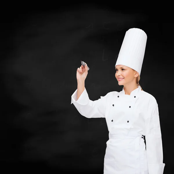 Smiling female chef writing something on air — Stock Photo, Image