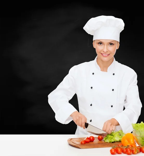 Glimlachend vrouwelijke chef-kok hakken groenten — Stockfoto