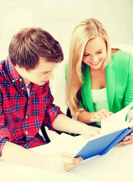 Studenti sorridenti che leggono un libro a scuola — Foto Stock