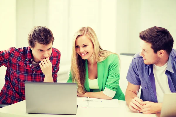 Smiling students looking at laptop at school — Stock Photo, Image