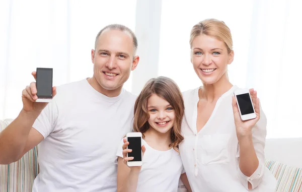 Föräldrar och liten flicka med smartphones hemma — Stockfoto