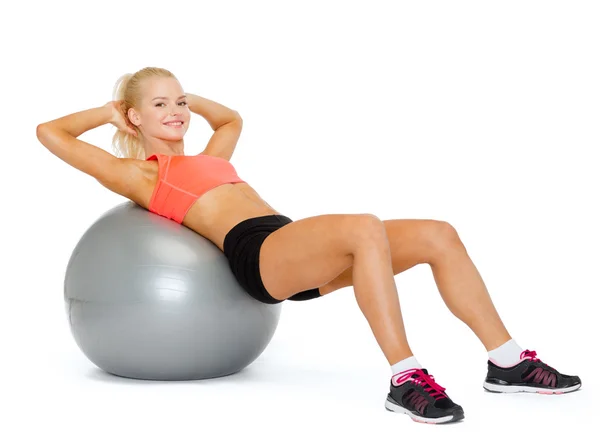 Sorrindo mulher desportiva exercitando na bola de fitness — Fotografia de Stock