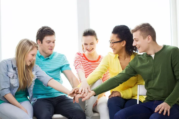 Smiling students with hands on top of each other — Stock Photo, Image