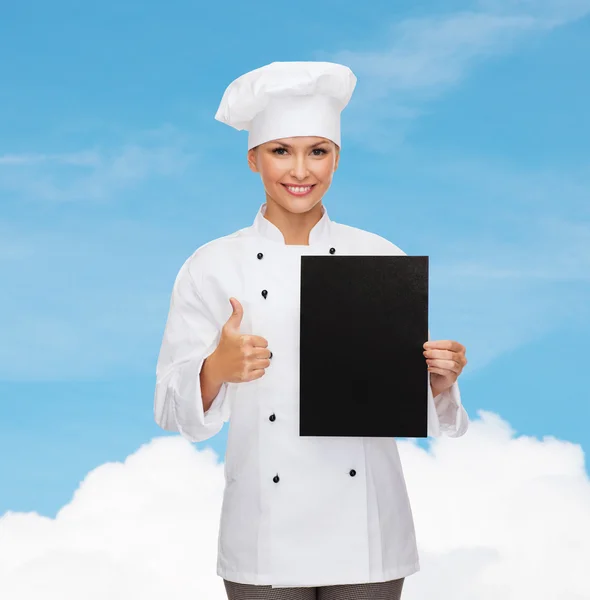 Smiling female chef with black blank paper — Stock Photo, Image