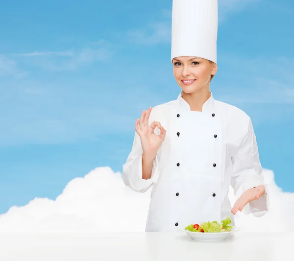 Chef feminino sorridente com salada no prato — Fotografia de Stock