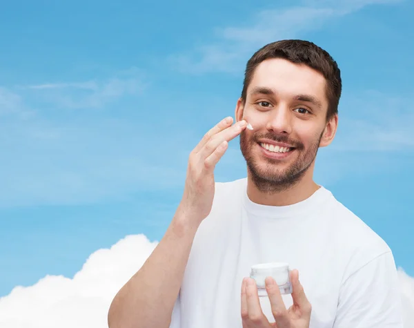 Beautiful smiling man applyin cream — Stock Photo, Image