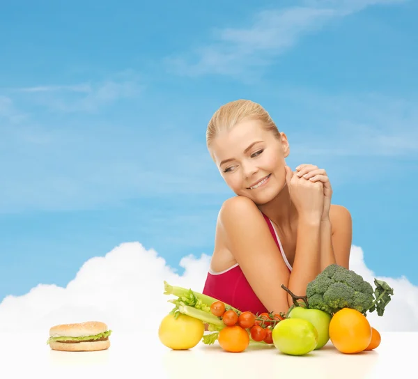 Pochybující žena s ovocem a hamburger Royalty Free Stock Obrázky
