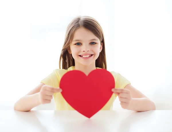 Lachende meisje met rood hart thuis — Stockfoto