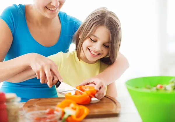 Glimlachend meisje met moeder hakken peper — Stockfoto