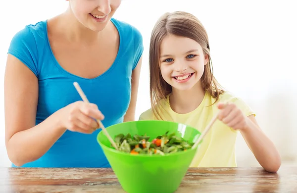 Маленькая девочка с маминым салатом на кухне — стоковое фото