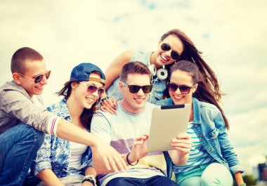 group of smiling teenagers looking at tablet pc clipart