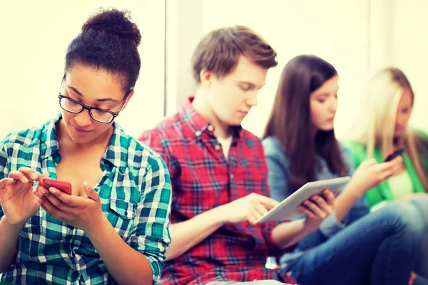 Estudiantes mirando dispositivos en la escuela — Foto de Stock