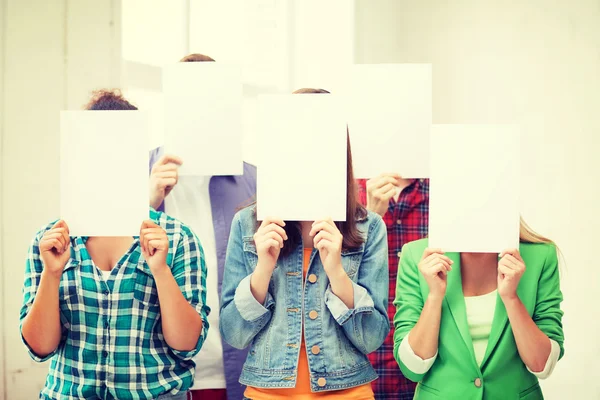 Studenten die betrekking hebben op gezichten met lege papieren — Stockfoto