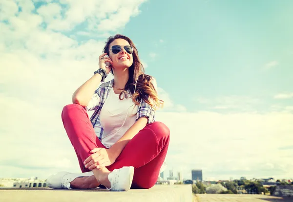 Adolescente souriante dans des lunettes avec écouteurs — Photo