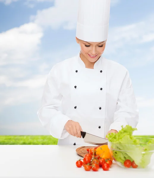 Sonriente hembra chef cortar verduras — Foto de Stock