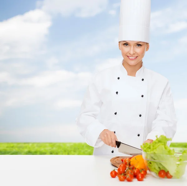 Sonriente hembra chef cortar verduras —  Fotos de Stock
