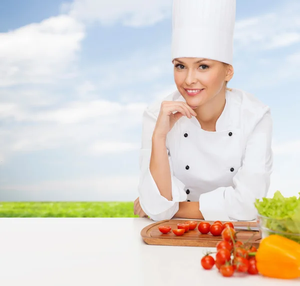 Chef feminino sorridente com legumes — Fotografia de Stock