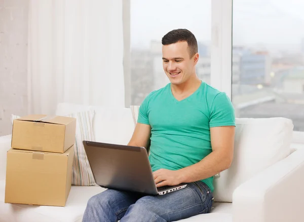 Homem com laptop e caixas de papelão em casa — Fotografia de Stock