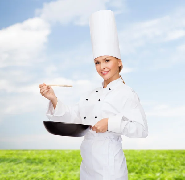 Lachende vrouwelijke chef-kok met pan- en -lepel Stockfoto