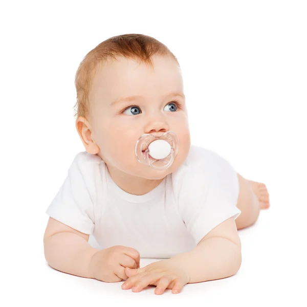 Smiling baby lying on floor with dummy in mouth — Stock Photo, Image