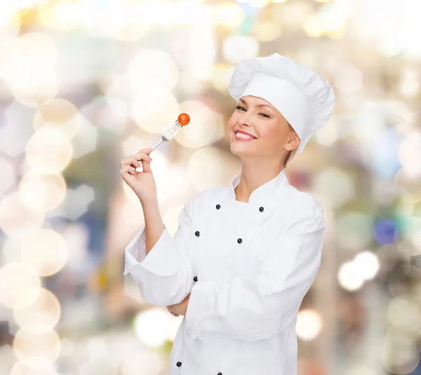 Chef feminino sorridente com garfo e tomate — Fotografia de Stock