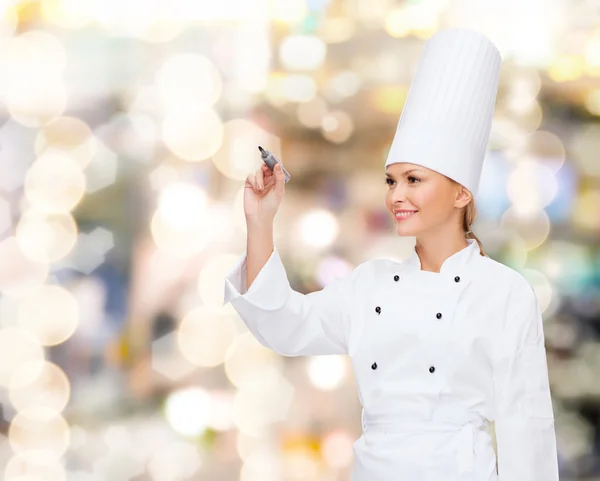 Sorrindo chef feminino escrevendo algo no ar — Fotografia de Stock