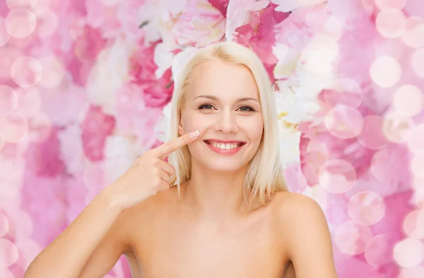 Usměvavá mladá žena ukazuje na nos — Stock fotografie