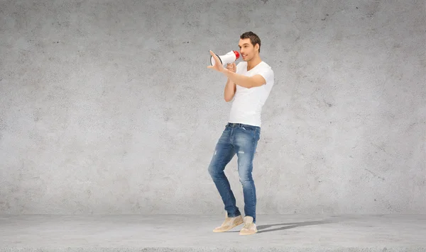 Handsome man with megaphone over concrete wall — Stock Photo, Image