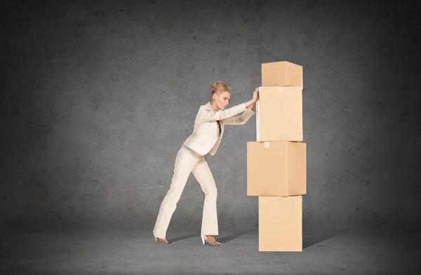 Businesswoman pushing tower of cardboard boxes — Stock Photo, Image