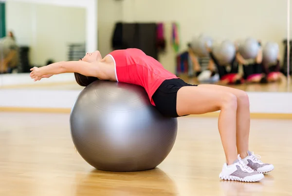 Молодая женщина делает упражнения на фитнес-мяч — стоковое фото