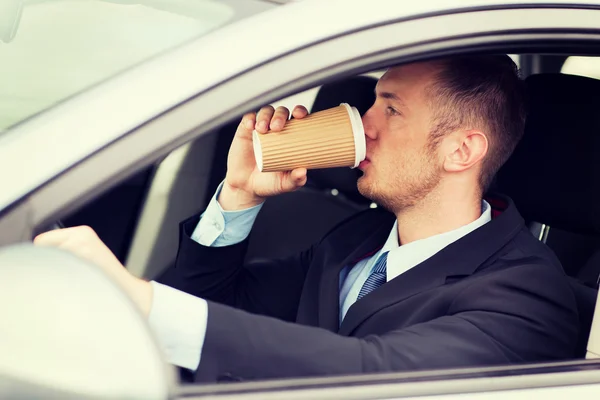 男は車を運転している間コーヒーを飲む — ストック写真