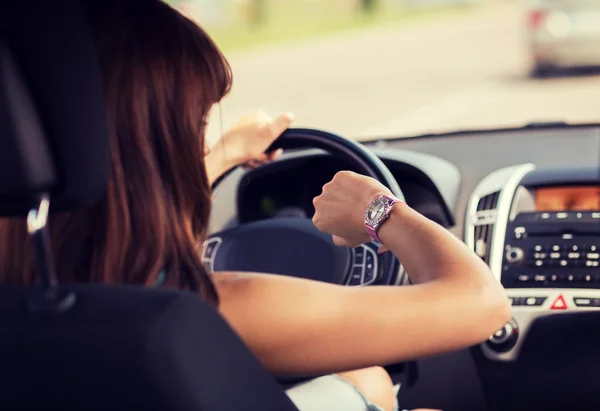 Mujer conduciendo un coche y mirando el reloj — Foto de Stock