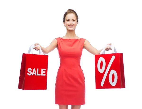 Mujer joven en vestido rojo con bolsas de compras —  Fotos de Stock