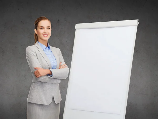 Smiling businesswoman standing next to flipboard — Stock Photo, Image