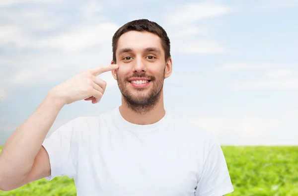 Lächelnder junger gutaussehender Mann zeigt auf Augen — Stockfoto