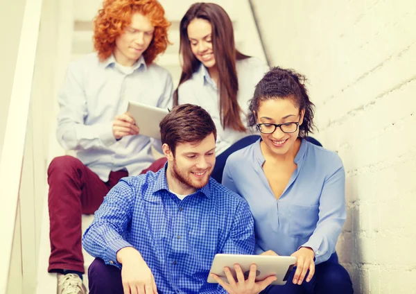 Team with tablet pc computer sitting on staircase — Stock Photo, Image