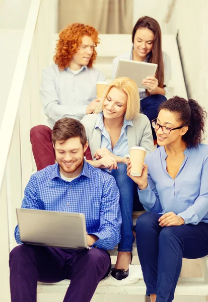 Team with laptop and tablet pc on staircase — Stock Photo, Image