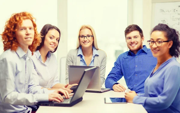 Equipe sorridente com laptop e mesa pc computadores — Fotografia de Stock