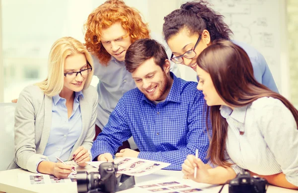 Equipo sonriente con cámara fotográfica e imágenes en la oficina — Foto de Stock