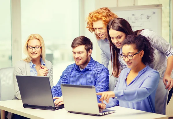 Equipe sorridente com computadores portáteis no escritório — Fotografia de Stock