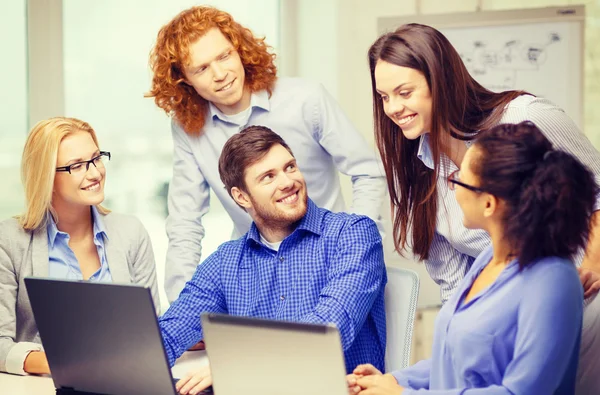 Équipe souriante avec ordinateurs portables au bureau — Photo