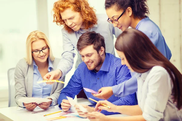 Lächelndes Team mit Farbmustern im Büro — Stockfoto