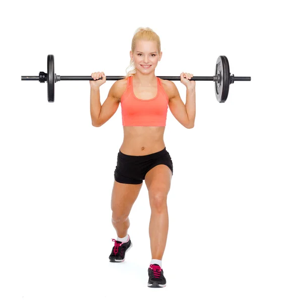 Sorrindo mulher desportiva exercitando com barbell — Fotografia de Stock