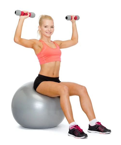 Frau mit Kurzhanteln sitzt auf Fitnessball — Stockfoto