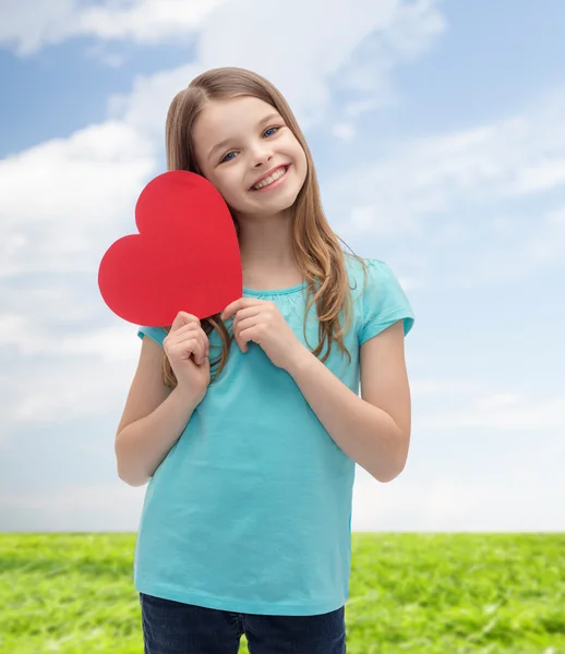 Kırmızı kalpli küçük kız gülümseyerek — Stok fotoğraf