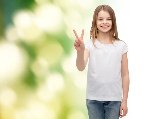 Mała dziewczynka w białej koszulce pokazując gest pokoju — Zdjęcie stockowe