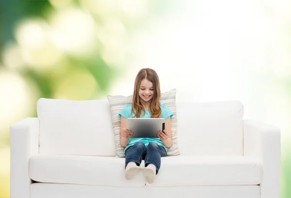 Kleines Mädchen sitzt auf Sofa mit Tablet-PC — Stockfoto