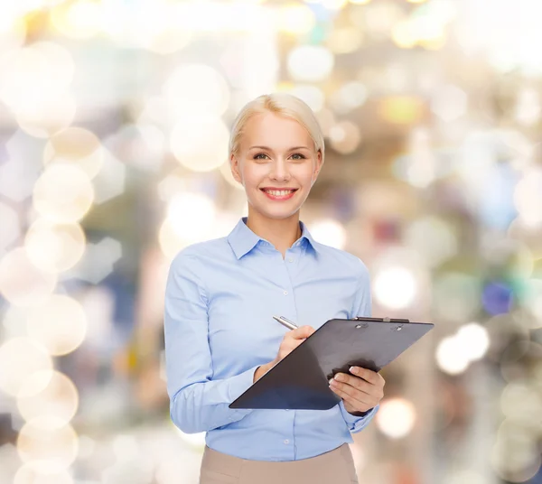 Mujer de negocios sonriente con portapapeles y pluma — Foto de Stock