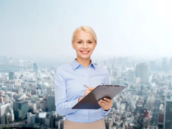 Mujer de negocios sonriente con portapapeles y pluma — Foto de Stock