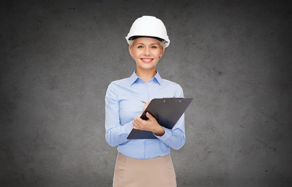 Smiling businesswoman in helmet with clipboard — Stock Photo, Image